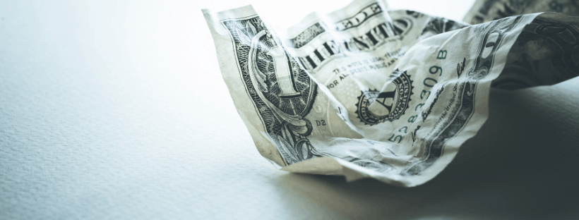 A crumpled one-dollar bill resting on a light surface, highlighting the intricate details and textures of the worn currency.