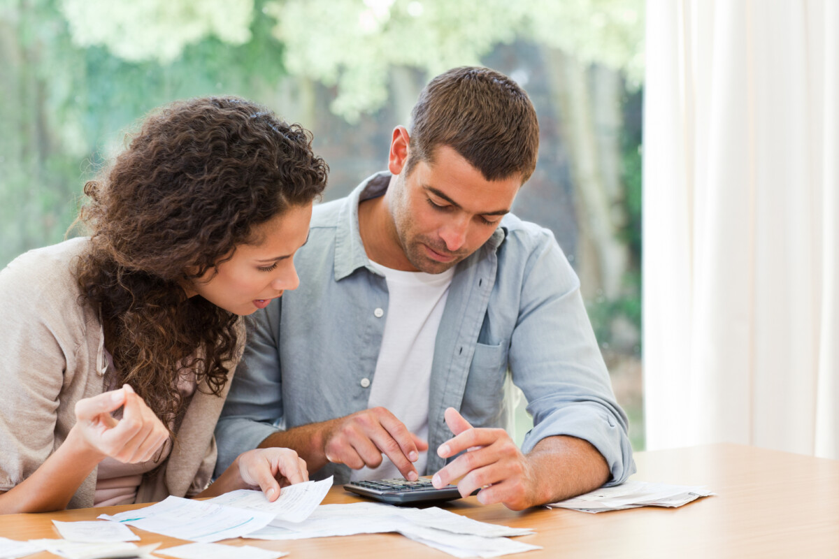 Couple at a table evaluating their budget and wondering how being in debt affects their financial future.