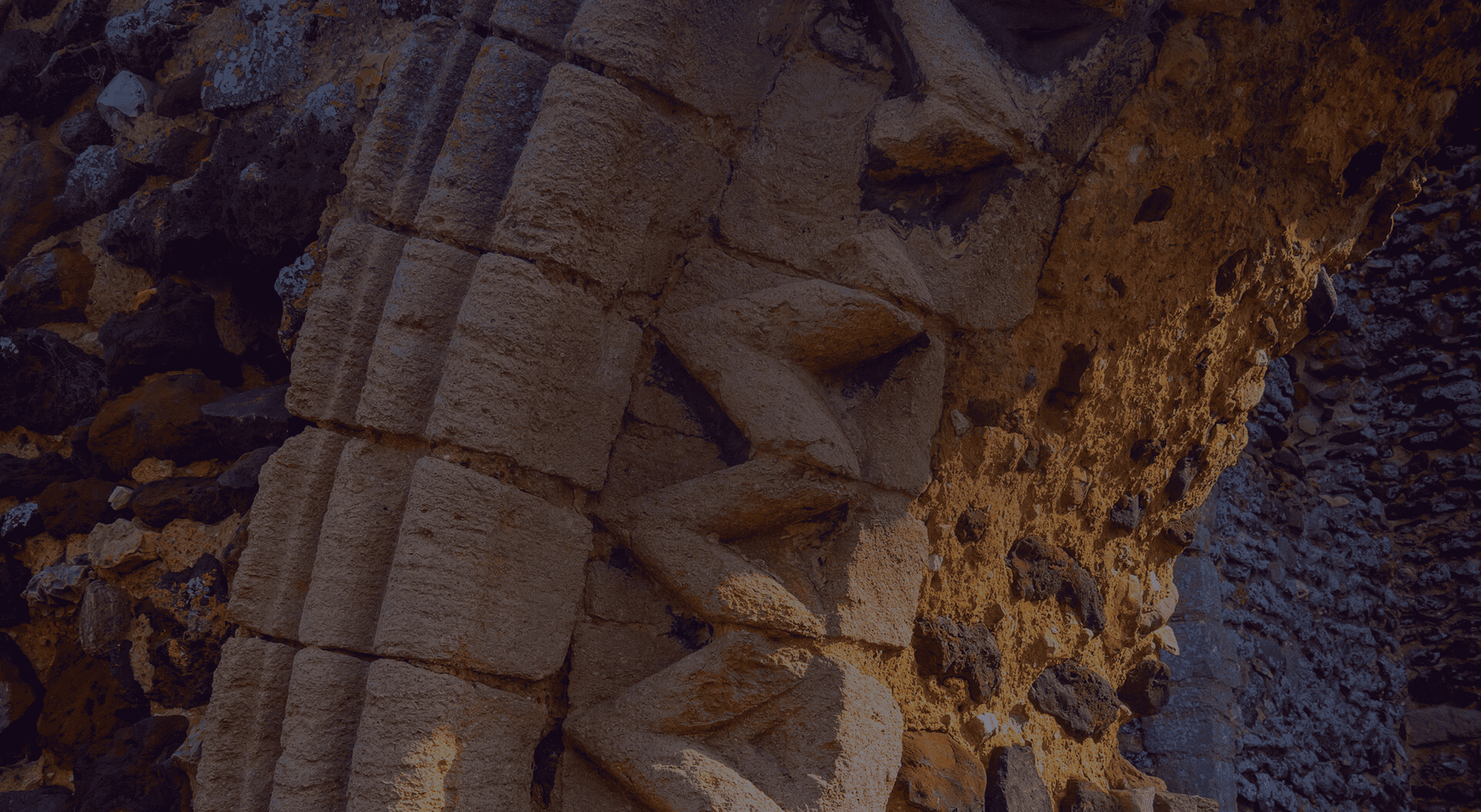 Ancient stone columns with intricate carvings shrouded in shadow, testifying to the enduring craftsmanship of a bygone era.